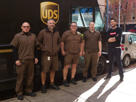 A photo of UPS employees standing in front of a UPS truck