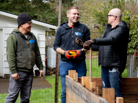 A photo of three volunteers talking and smiling in a garden