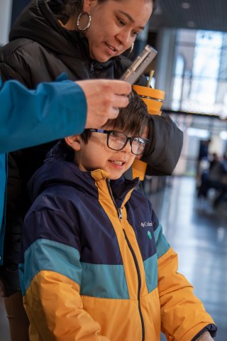 A child in glasses looks closely at a display