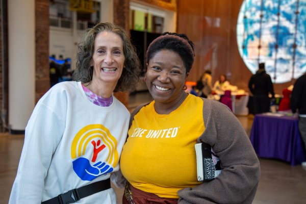 two men in United Way shirts smile for the camera with families behind them