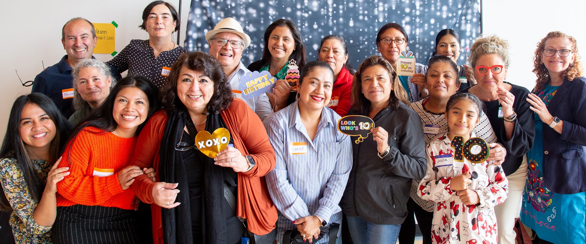 A large group of people holding props smile for the camera