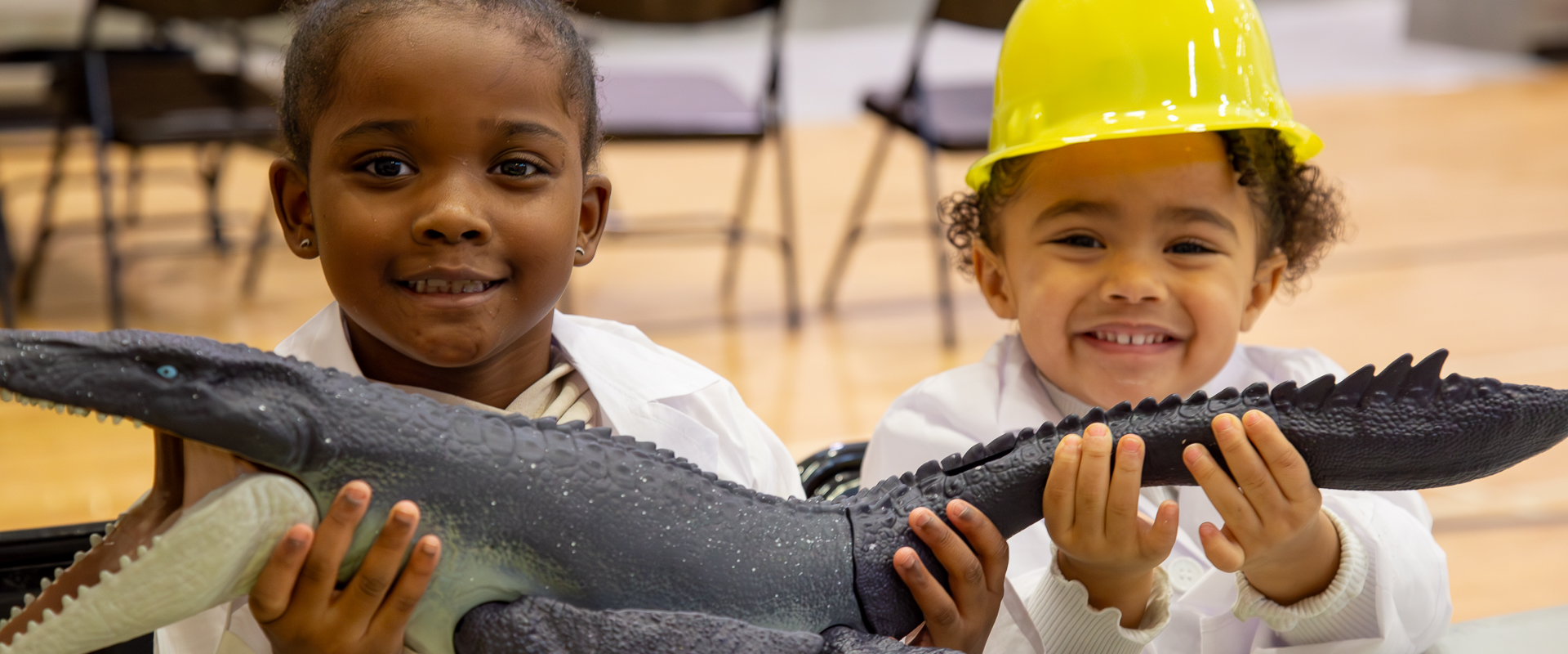 two young girls hold a dinosaur toy