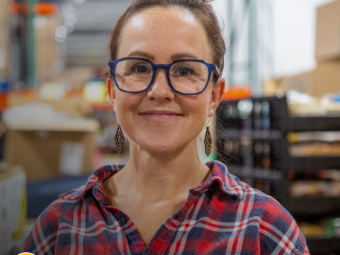 A woman smiles in a warehouse