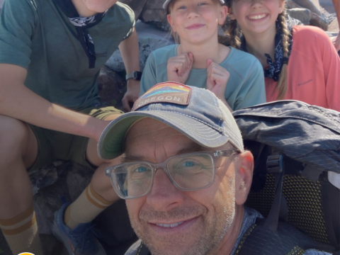 A man smiles with kids behind him